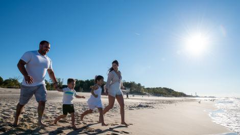 Familia corriendo por la playa en la región de Indiana Dunes