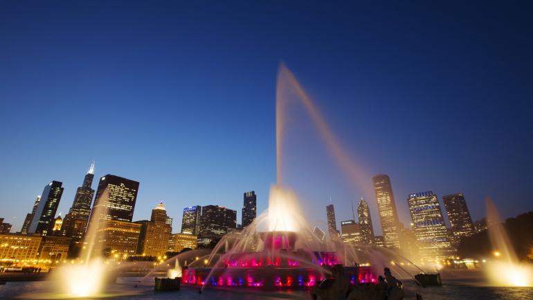 An illuminated scene of Buckingham Fountain in the center of Grant Park