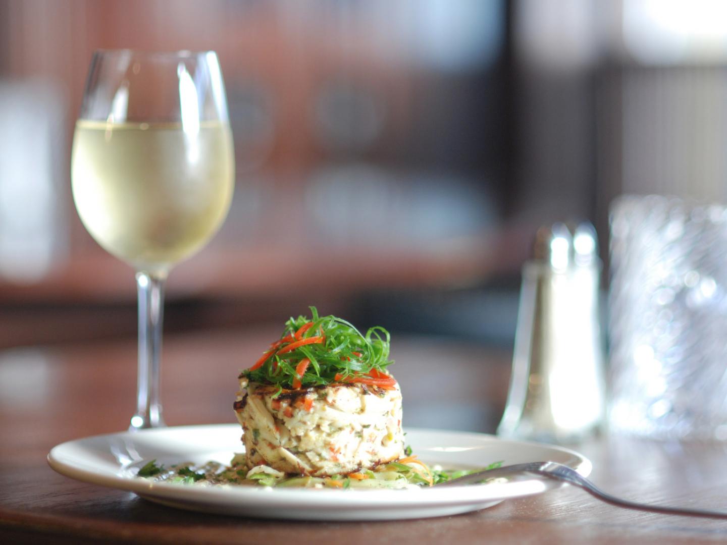 ニューオーリンズのレストランで提供される美しい盛り付けの料理とグラスワイン