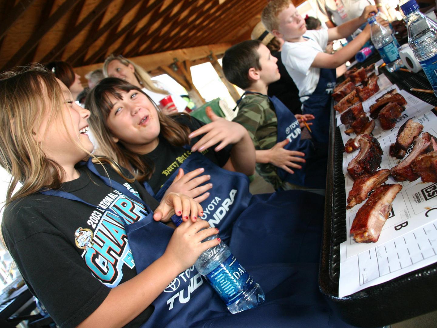 Kids enjoying ribs during the WhistleStop Bar-B-Que Weekend in Huntsville, Alabama