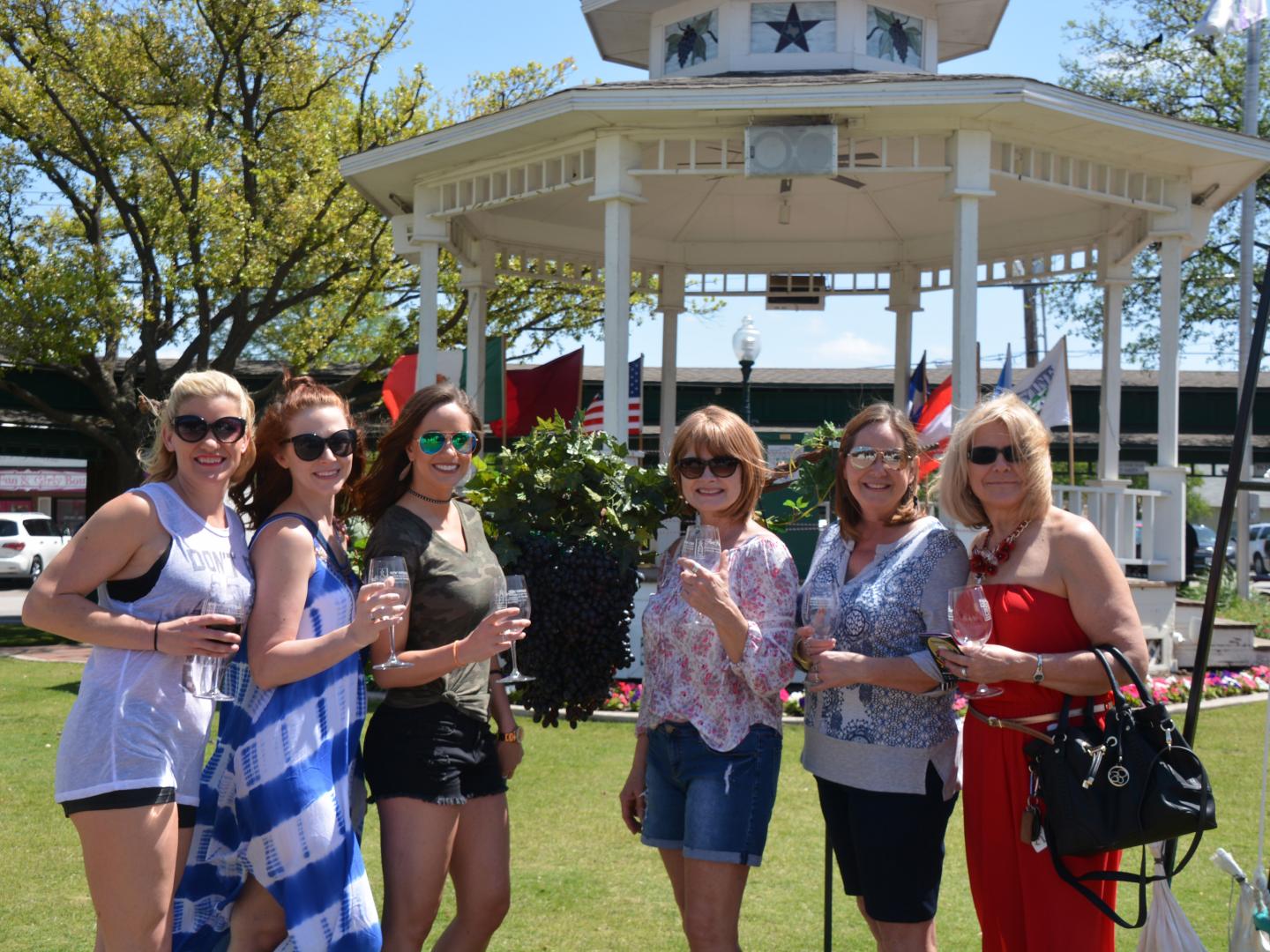 テキサス州グレープバインで開催されるニュー・ビンテージ・ワイン＆ギャラリー・トレイル＆ブレッシング・オブ・ザ・ヴァインズでワインを片手にポーズをとる人たち