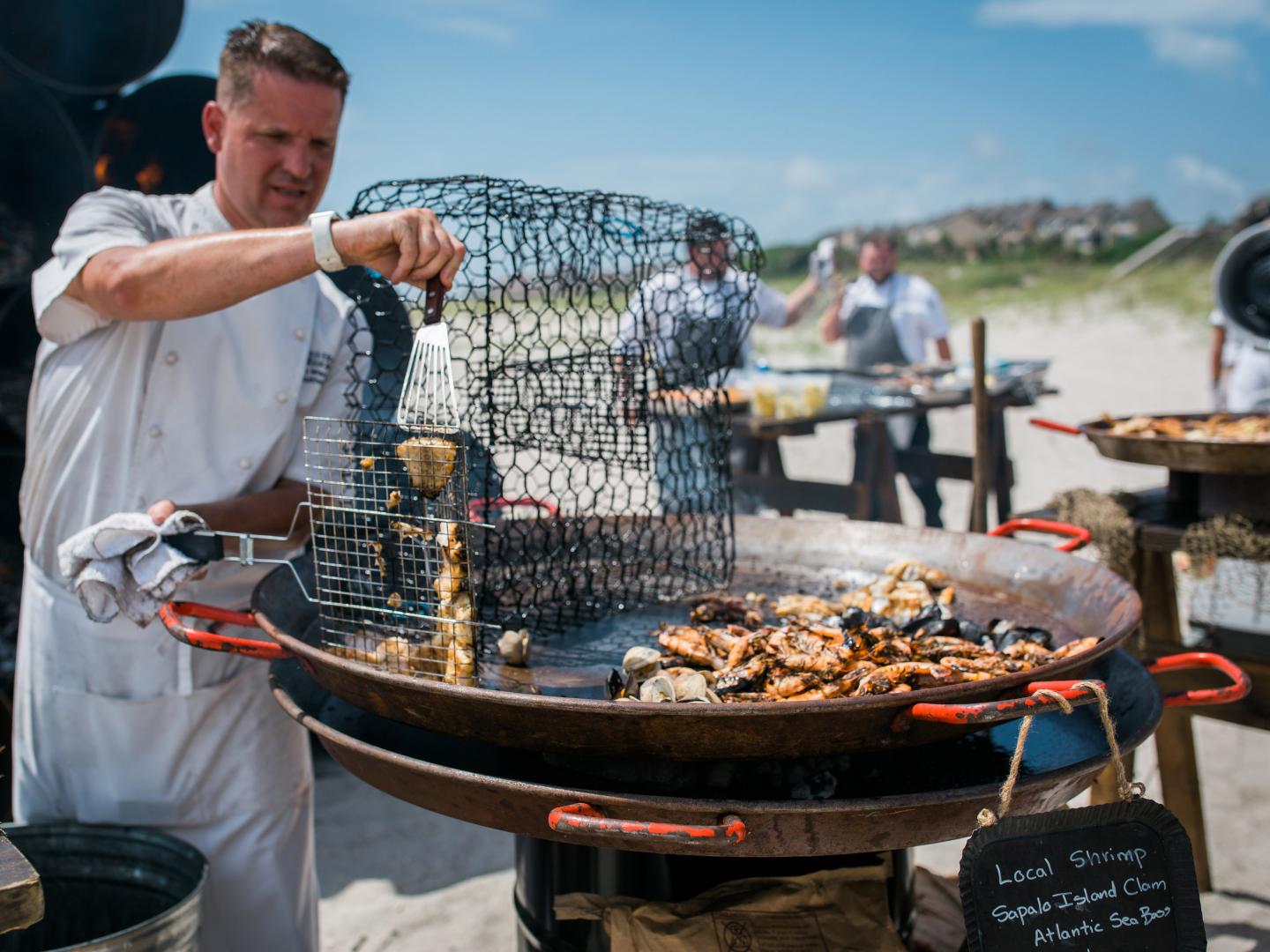 A chef creating a local shrimp dish on the beach during Fish to Fork at the Omni Amelia Island Plantation in Florida