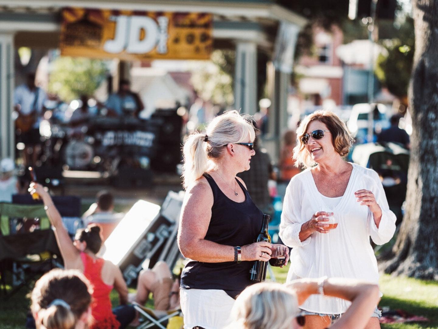 Friends sipping wine during the Concerts in the Park event in Paso Robles, California