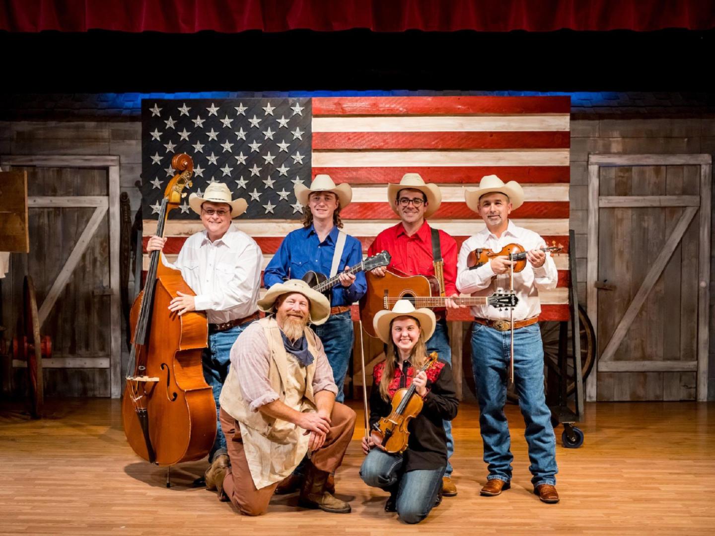Performers at the The Great American Chuckwagon Dinner Show pose in front of an American flag in Branson, Missouri