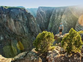 Ein Wanderer am Abgrund der gefurchten Felswände des Black Canyons im Gunnison-Nationalpark, Colorado