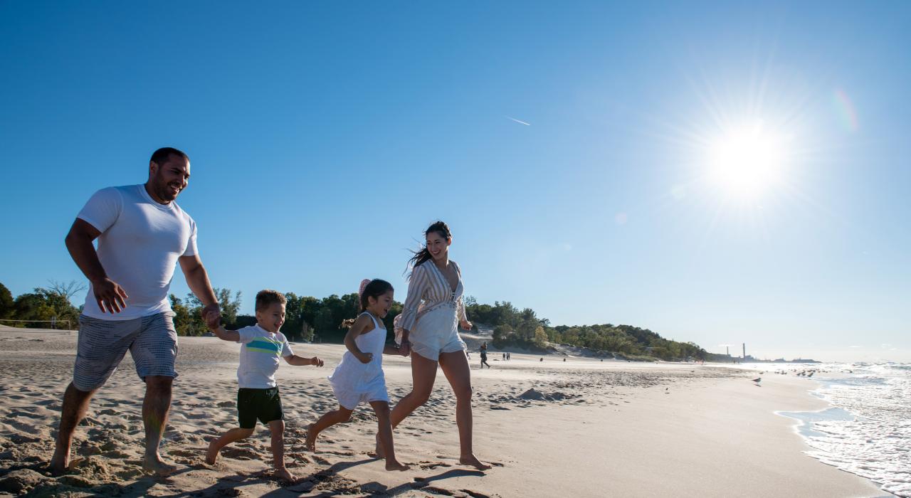 Familia corriendo por la playa en la región de Indiana Dunes